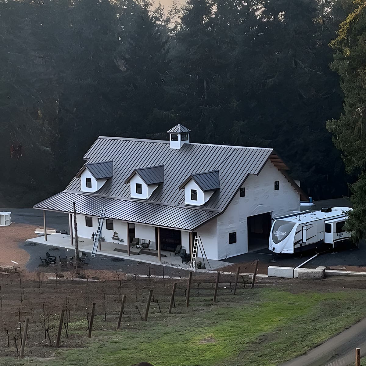 White farmhouse barn featuring gray metal roofing.